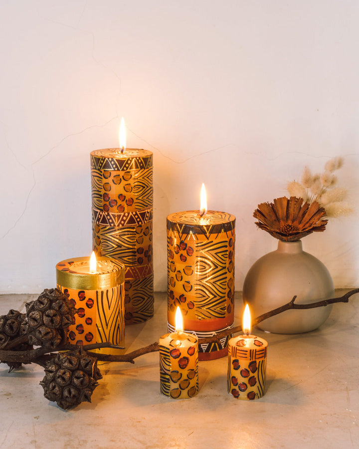 Animal Print lifestyle photo with 3x4 pillar, 3x6 pillar, 3x8 pillar as well as 2 votives.  All burning brightly with natural dry flowers at the sides.