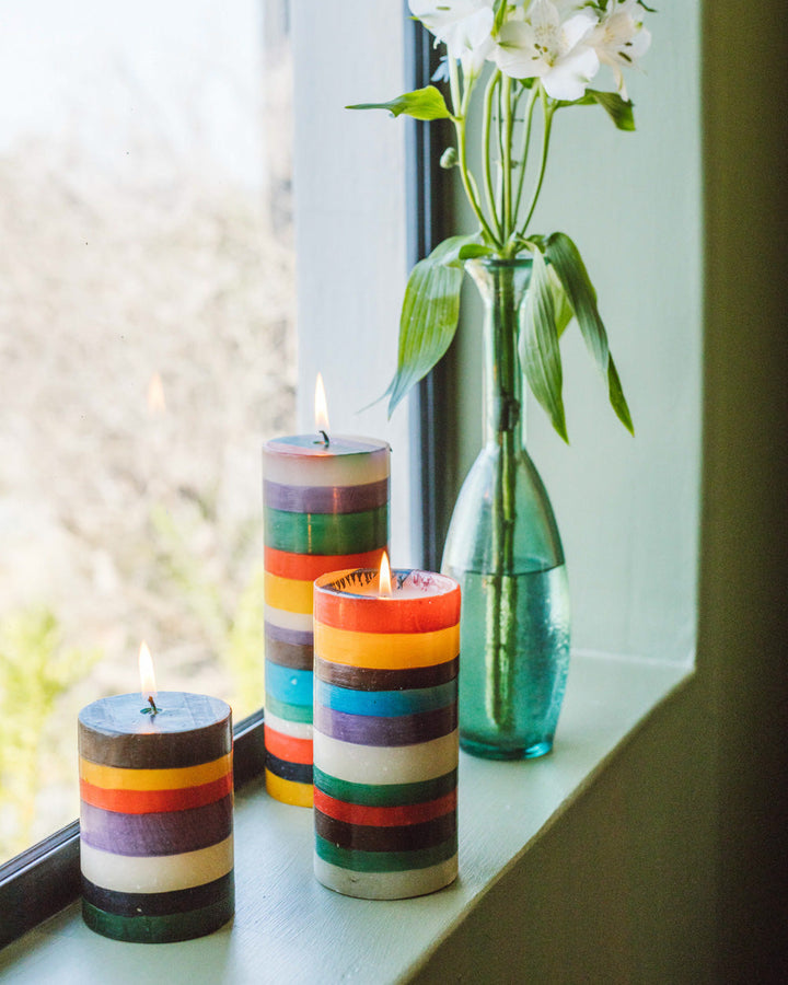 Lifestyle photo of the Memphis Stripe pillars, 3x4, 3x6, and 3x8. All lit and next to a vase with flower standing in a window.  Colorful, clean & fun!