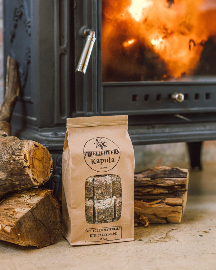 Photo of Kapula Firelighters bag full of lighters, in front of logs and burning fire