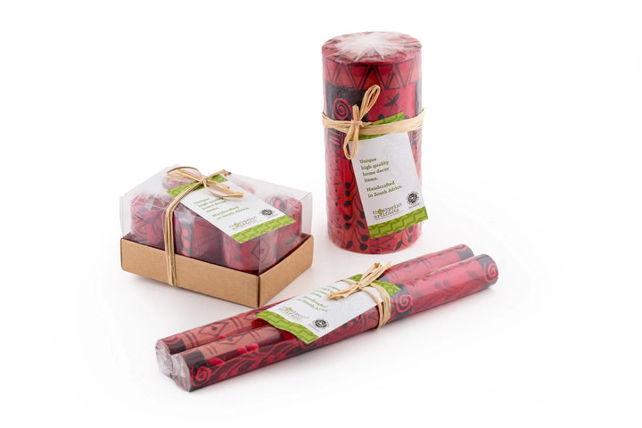 Berry Blaze candles in packaging; votives individually wrapped in a  6 pack box, pillar & cubes are individually wrapped and tied with story card, tapers are in a matched pair, individually wrapped and tied with a story card. All sustainable packaging.