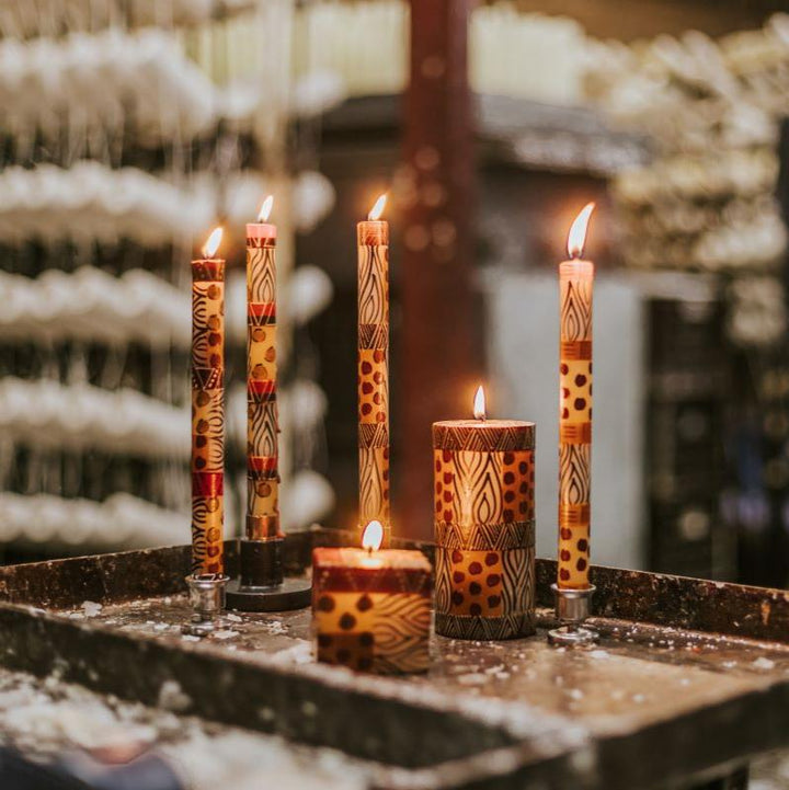 Lifestyle photo of  Animal Print tapers, cube and pillar burning brightly with the factory muted in the background.