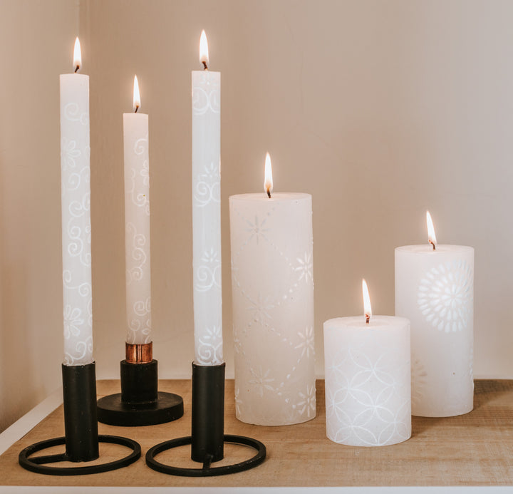 Lifestyle of White on White tapers in back taper holders with a white on white pillar in each size. All burning brightly.  As the candles burn down the artistry shows beautifully!