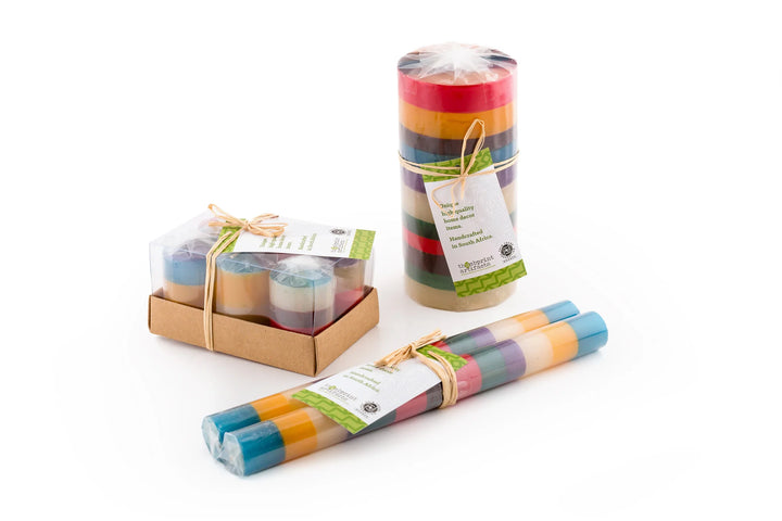 Memphis Stripe candles showing how the candles are packaged.  Pillars & cubes are wrapped and tied with story card. Taper pair are individually wrapped and tied together with a story card.  Votives are wrapped individually in a 6-pack box. All sustainable packaging.