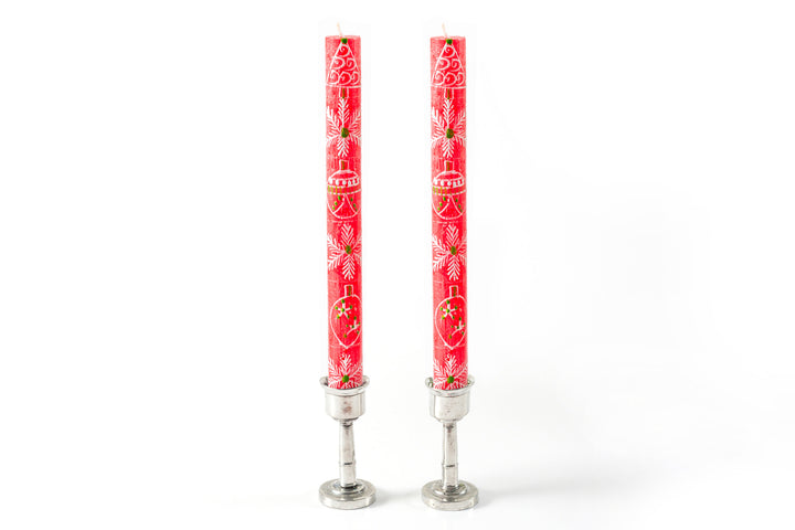 Whimsy Christmas red taper pair in pewter taper holders. The tapers are red base color with hand panted with trees, snow flakes and Christmas ornaments in white with touches of green.