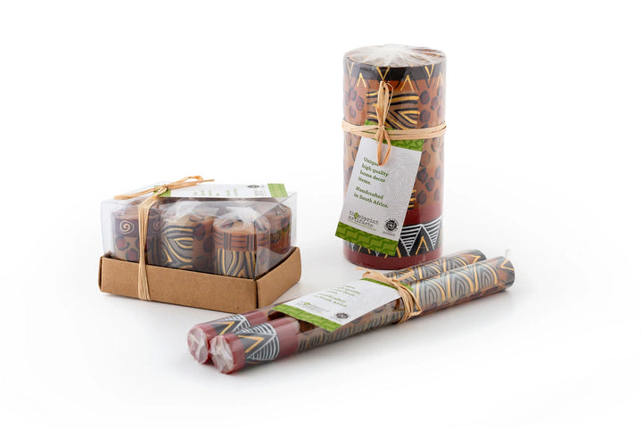 Photo of the packaging of the candles; votive 6-pack gift box, pillar wrapped with story card, and matched taper pair tied with story card.  Fair Trade products. 