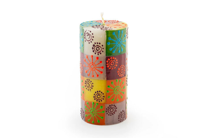 Magic Garden 3" x 6" pillar candle. The pillar is a white base with green, orange, turquoise, and lavender stripes. Overlay of pigment colors with a variety floral and leaf designs.