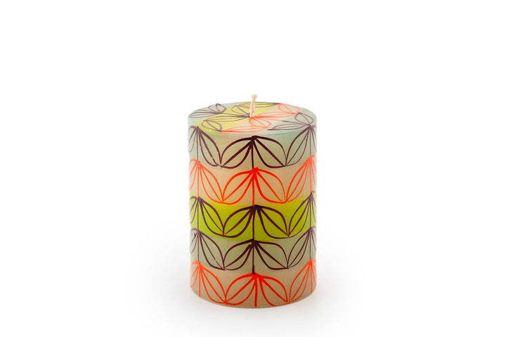 Magic Garden 3" x 4" pillar candle. The pillar is a white base with green, orange, turquoise, and lavender stripes. Overlay of pigment colors with a variety floral and leaf designs.