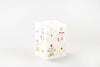 Whimsy Christmas 2" x 2' x 3" cubed candle. This one has a white base and  hand painted with  trees, snow flakes and Christmas ornaments painted in red, green and/or white.