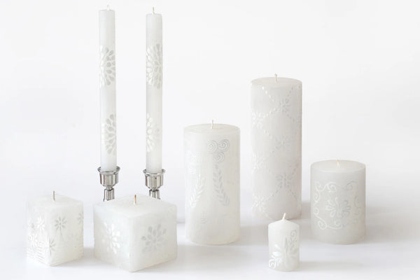 White on white collection of  hand painted candles have a floral or graphic design painted in white on a white candle. Beautiful as they burn as the candle lights from within and shows the artistry on the candle. Fair Trade home decor.