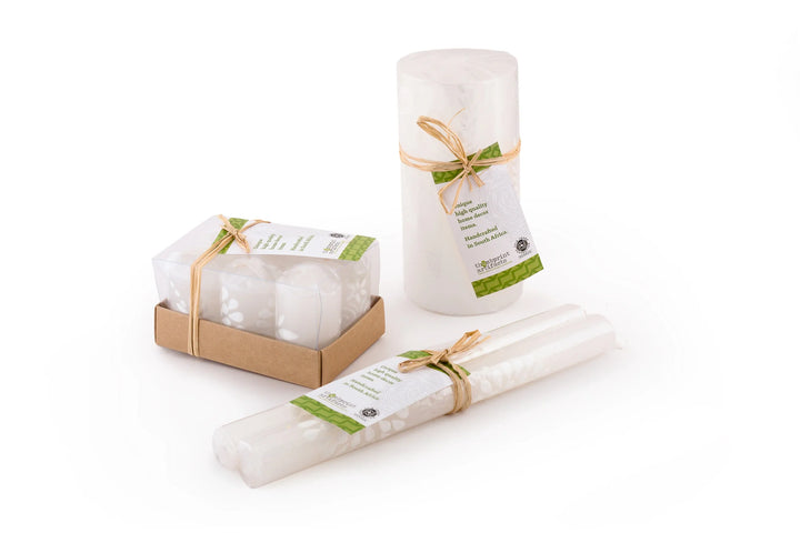 Packaging of candles; votives are individually wrapped and in a 6-pack gift box with story card, pillars & cubes are wrapped and tied with story card, tapers are matched pair, wrapped and tied with a story card.